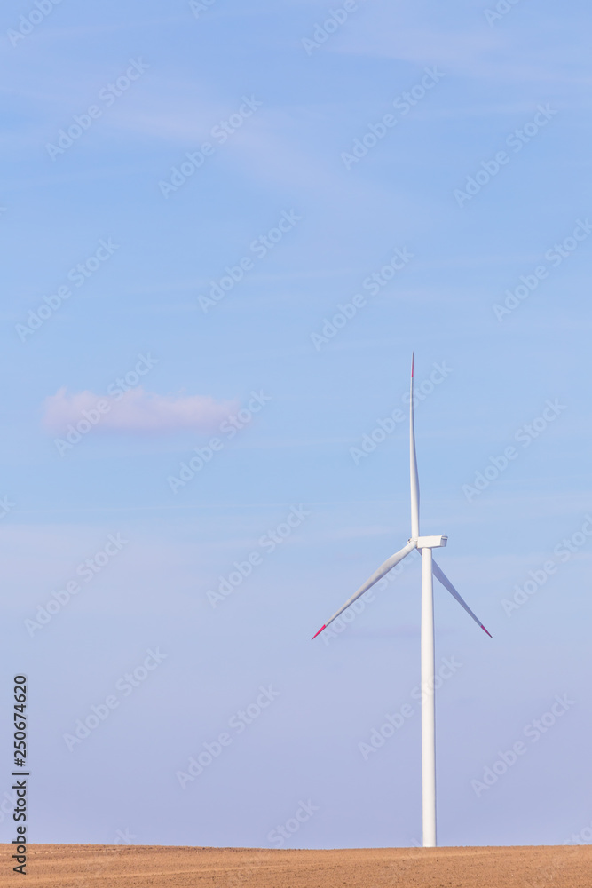 One single windmill turbine on agricultural field with blue sky in background. Renewable energy wind turbine One single windmill turbine on agricultural field with blue sky in background. Renewable energy wind turbine