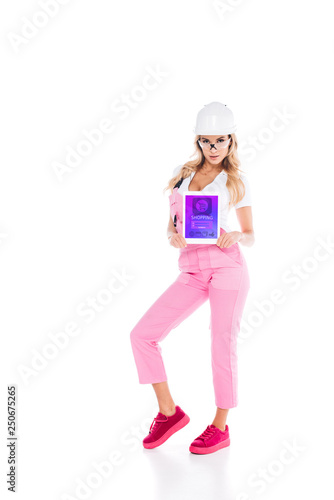 attractive handy woman in pink uniform holding digital tablet with shopping app on screen on white background