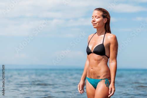 Young woman in a bikini wet from swimming in the sea