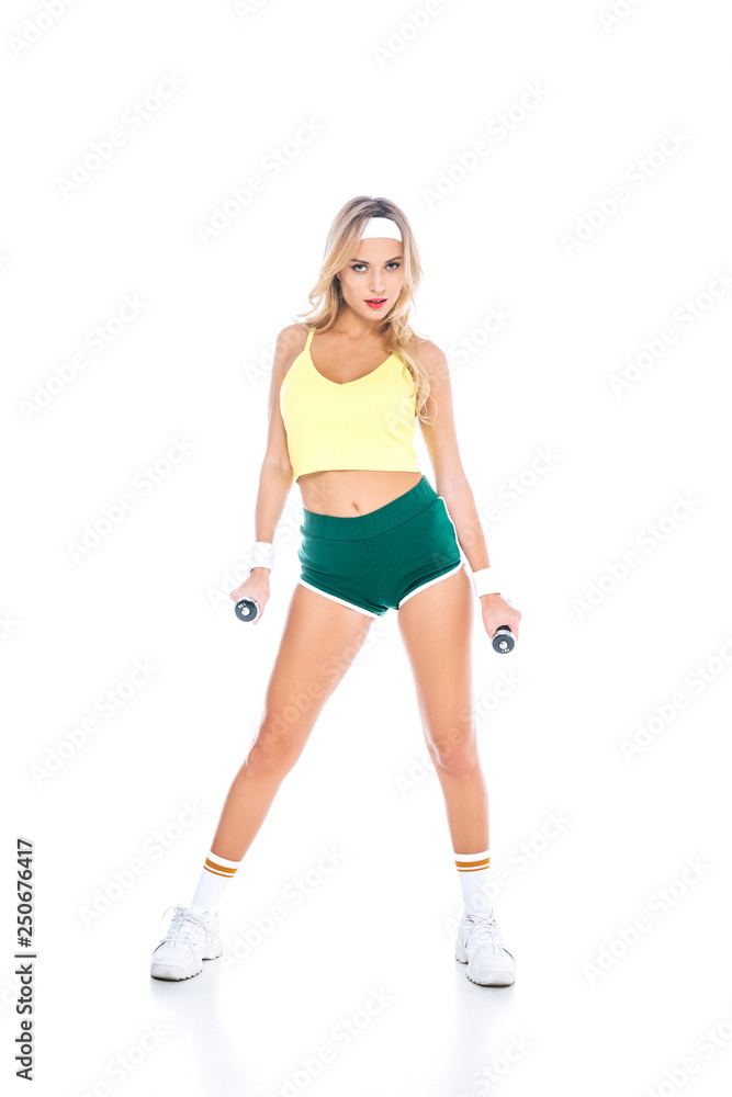 attractive blonde fitness trainer in green shorts and yellow singlet with dumbbells on white background attractive blonde fitness trainer in green shorts and yellow singlet with dumbbells on white background