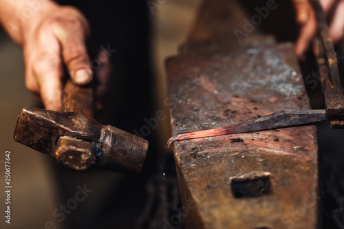 blacksmith makes an artistic forging of hot metal on the anvil. photo