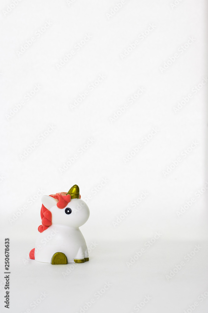 Small cute white unicorn toy with coral hair on a white empty background. Isolated. Copy space. Symbol. Kid. Colour. Vertical Small cute white unicorn toy with coral hair on a white empty background. Isolated. Copy space. Symbol. Kid. Colour. Vertical
