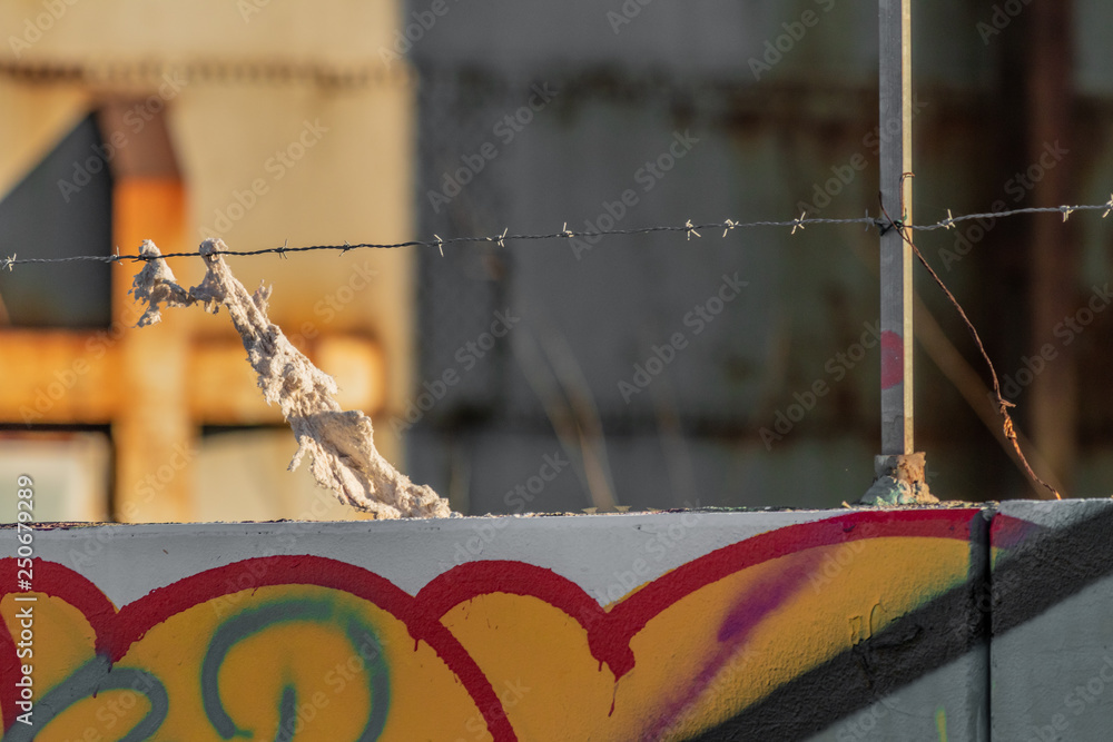 War and political refugees concept. Barbed wire fence detail, torn clothing strips from escape route. European and American closure, closed borders. African, Mexican and middle eastern migration flux.
