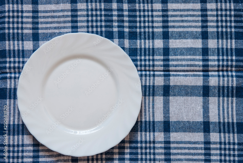 Empty plate on colorful tablecloth in an old wooden table Empty plate on colorful tablecloth in an old wooden table