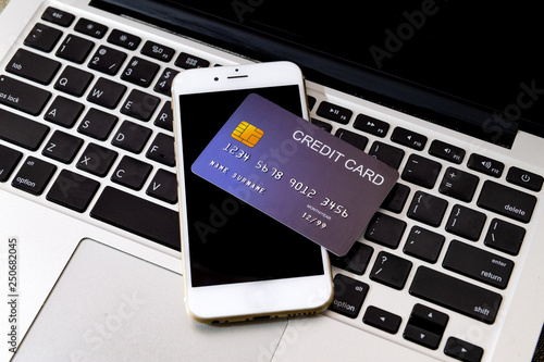 Credit Card put on mobile phone and laptop keyboard for preparing to pay