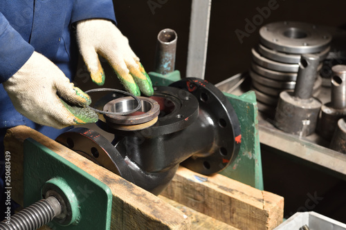 Fotografía The base for the valve is installed and clamped in a vice for assembly at the factory and the worker installs and fastens the components