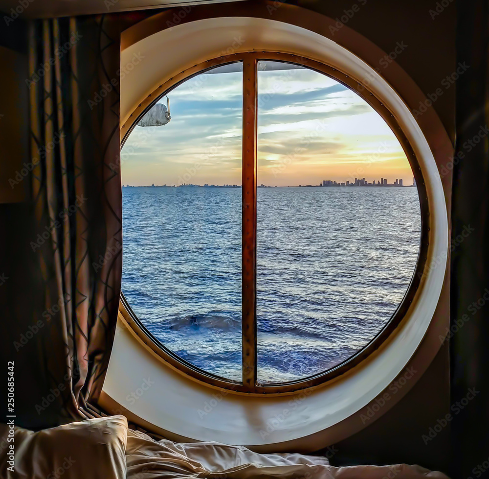 A view from the porthole window of a cruise ship, showing the city