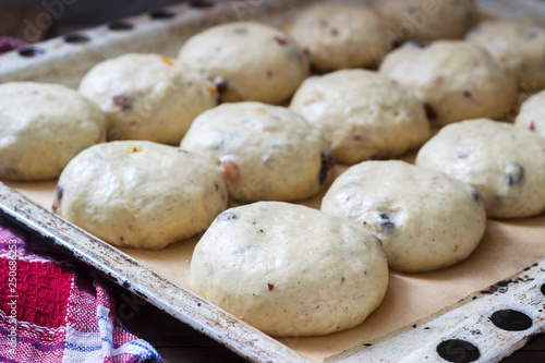 Baking tray with round uncooked cross buns on a wooden table. photo