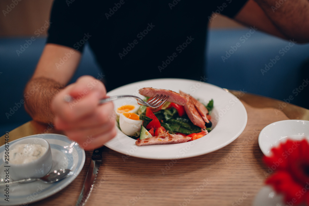 A young man is having breakfast in a restaurant at a round table. A young man is having breakfast in a restaurant at a round table.