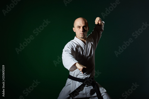 In karategi, an athlete perfom formal karate exercises on a dark green background