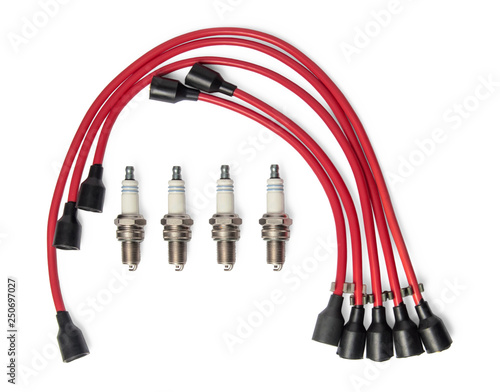 Four spark plugs and red wires of a high pressure are isolated on white background. Car parts. Top view.
