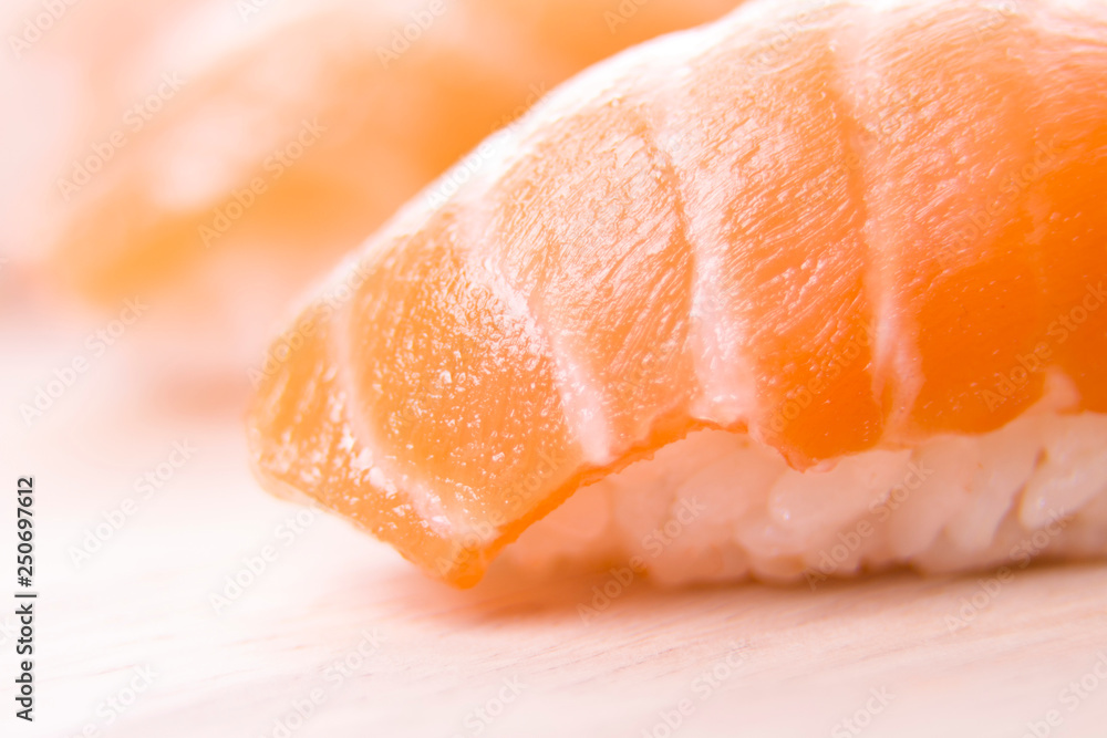 set of sushi on a wooden board with leaves of plants on a dark background