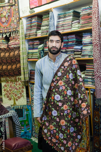 Seller from Kashmir in his colorful carpets store.Shallow doff