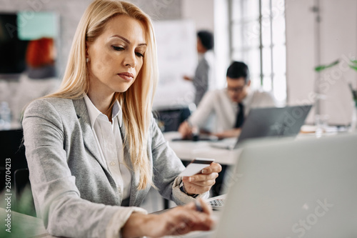 Serious businesswoman checking her online bank account while working in the office.