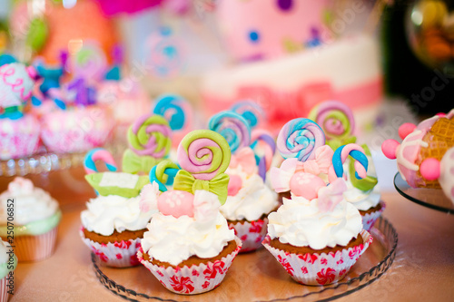 Pink and blue cupcakes with colored lollypops for candy bar