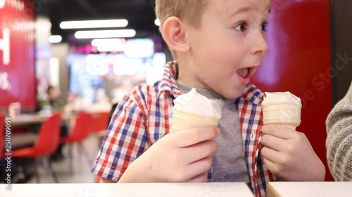 Surprised cute little boy with two waffle ice cream cups