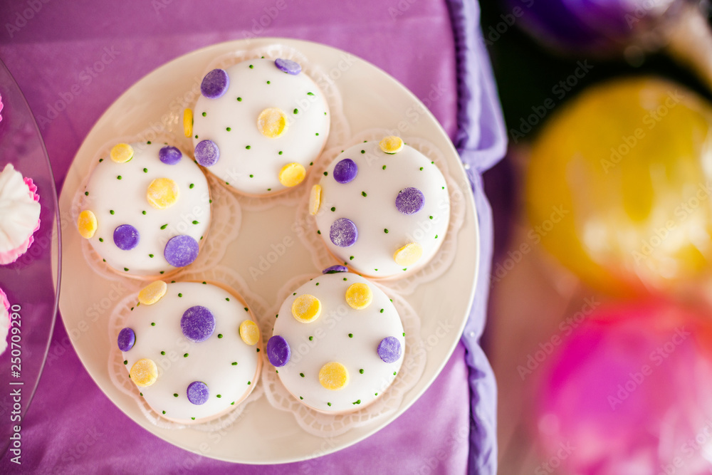 Candy bar for the birthday. White round cakes with big yellow and purple dots and with small green dots. Top view