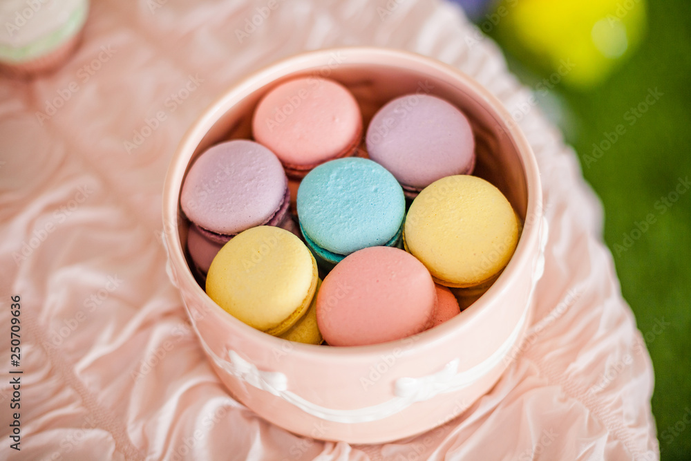 Candy bar for the first birthday for little baby girl. Sweet table and nice pink, blue, purple, yellow macaroons in the round pink box on the light pink table. Candy bar for the first birthday for little baby girl. Sweet table and nice pink, blue, purple, yellow macaroons in the round pink box on the light pink table.