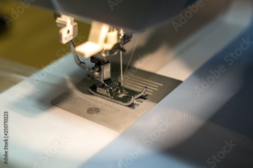 close up mechanism of sewing machine foot with needle and thread