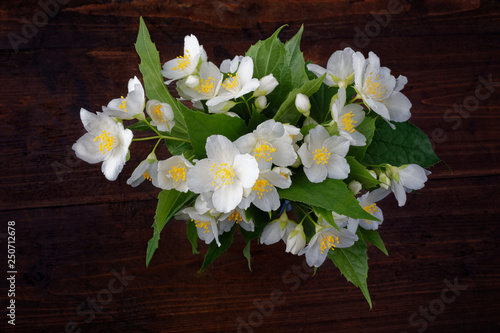 Jasmine bouquet on a dark rough wooden background. A bouquet of white flowers on a dark background. Spring still life.