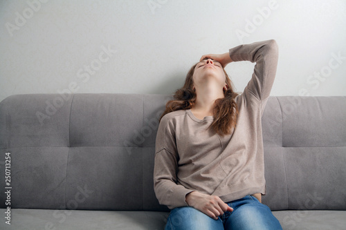  Young woman sitting on the couch depressed.