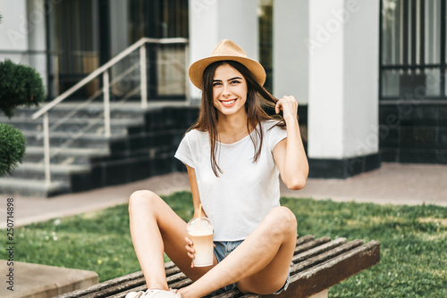 Brunette pretty tourist girl outdoor with cup of cold coffee.