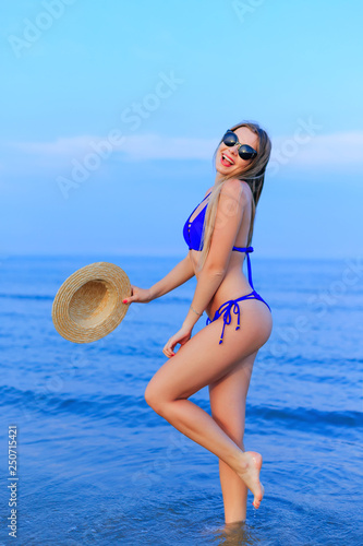 sexy girl with sunglasses in blue swimsuit poses on the backgrou