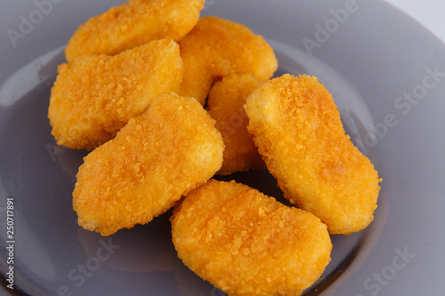 Chicken nuggets with cheese on a glass plate.