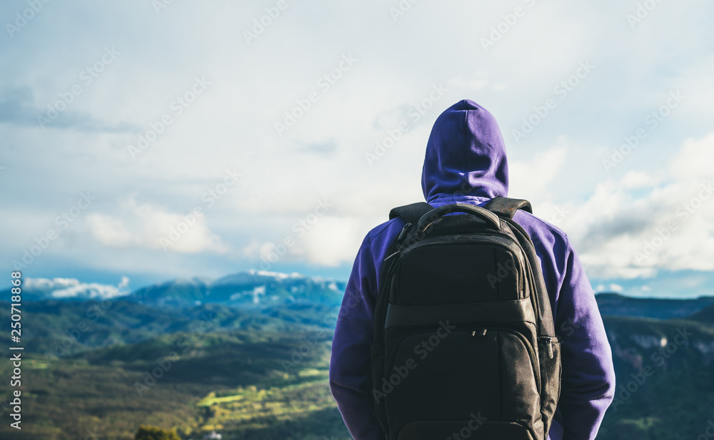 tourist traveler with black backpack on background top mountain, traveler look at blue sky clouds, hiker enjoying nature panoramic landscape in trip, relax holiday mockup concept in trekking trip