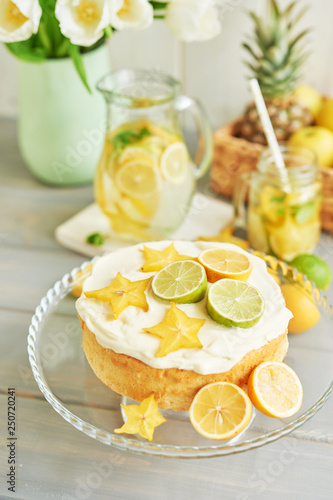 Naked cake with lemons and limes. Lemonade and flowers tulips on table. Mason jar glass of lemonade with lemons and straw. Copy space. Concept of spring and summer season. Healthy Food and Drink