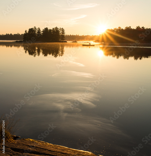 Man Canoeing at Sunrise on Lake (ID: 250720264)