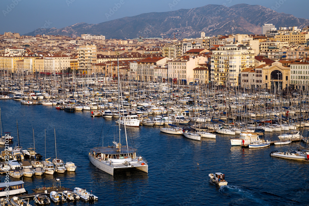 Aerial panoramic view of Marseille Old Port with yachts and boats and the city, mountains in the background. Marseille, Provence, France. Holidays in France.