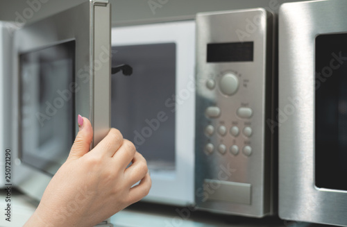 A young woman is choosing a new microwave oven for home.