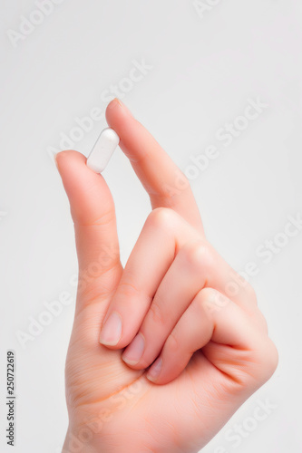 Woman hand holding pills on white background