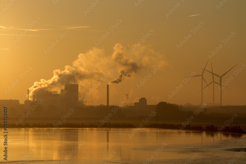 Wind turbines and industrial buildings at sunrise
