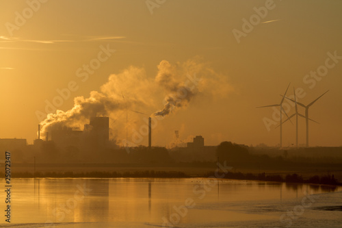 Wind turbines and industrial buildings at sunrise