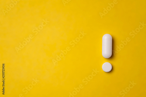 White tablets on yellow background. exclamation mark