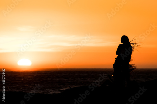 Sunset silhouette: same sex couple of girls at sunset in Camps Bay Tidal Pool, Cape Town, South Africa