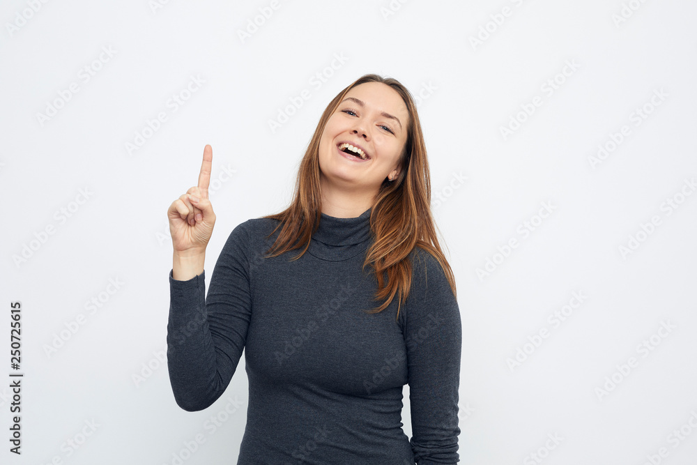 portrait of young smiling woman pointing up looking in camera portrait of young smiling woman pointing up looking in camera
