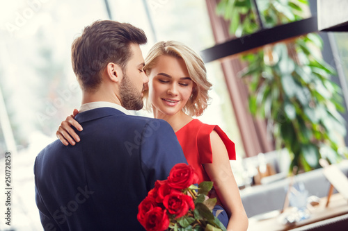 Young couple on date in restaurant dancing sensual holding bouquet