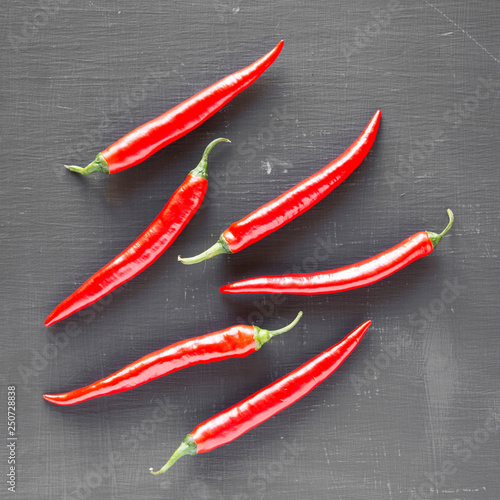 Hot red chili peppers on black surface, overhead. From above, top view, flat lay. Close-up.