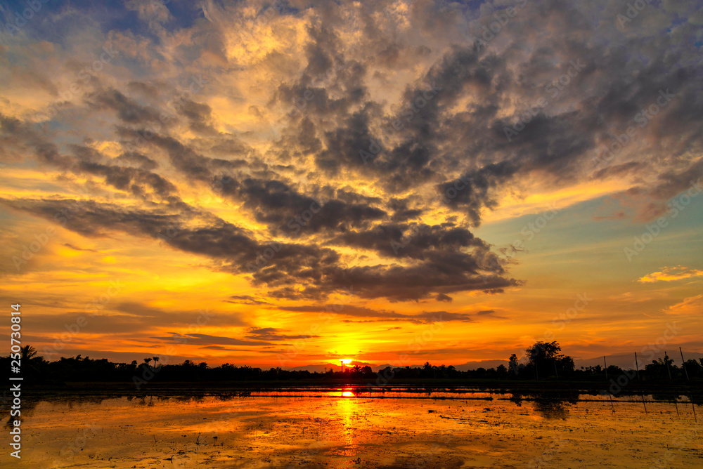 Orange and blue sky after sunset with reflecting in water surface. Countryside of Thailand.