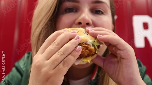 Close up tasty fried chicken burger in hands of plus size teen girl