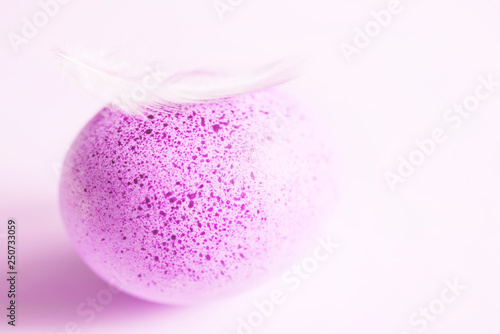 Pink Easter egg and feather on light pink background, soft focus	
