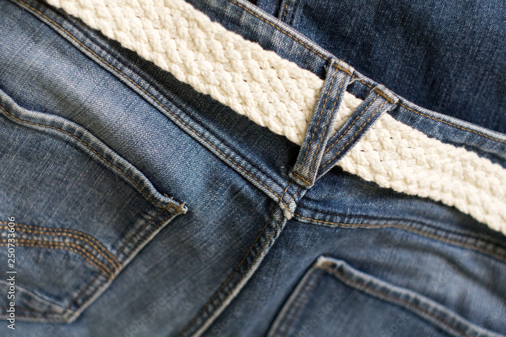 Blue jeans and white woven belt. Men's casual outfits. Texture of denim, background.