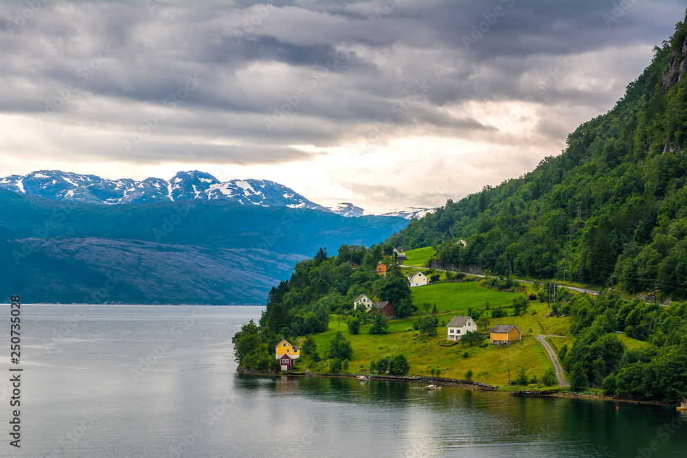 Amazing nature view with dramatic sky and wooden houses on the banks of the Norwegian fjord.  Scandinavian Mountains, Norway. Artistic picture. Beauty world.