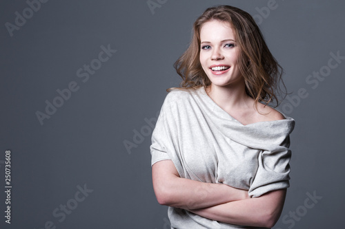Cute smiling woman on a gray background. Beauty and fashion.