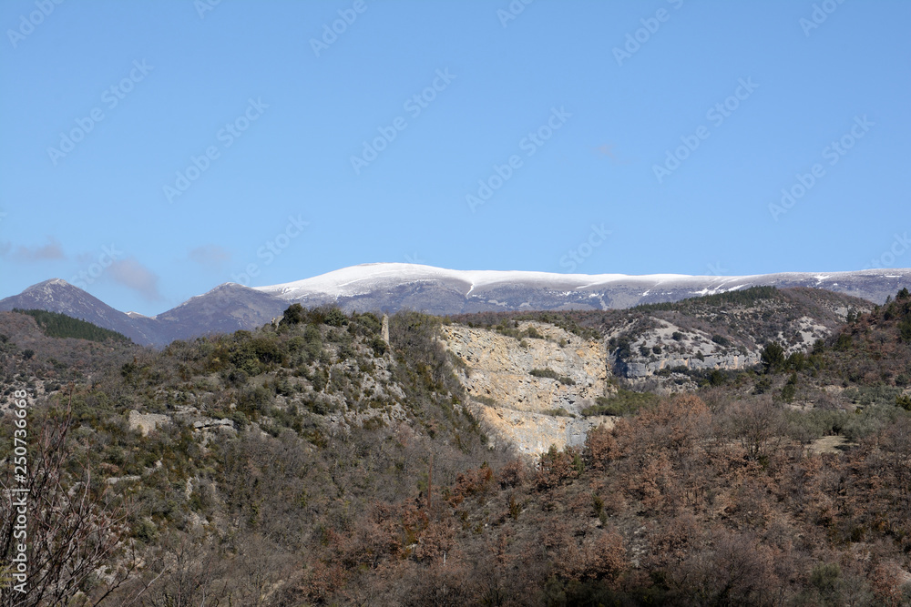Snowy mountain. Point of view from the french village of Curnier , with the ruins of a castle and a stone quarry in the center. France, Drome Provençale, Les Baronnies.