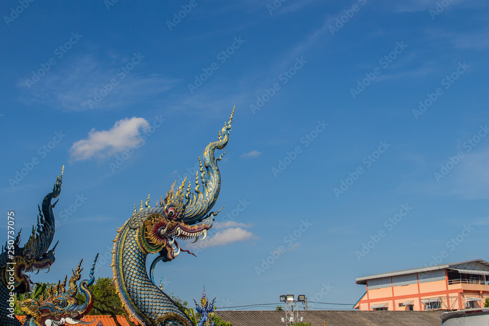 Fototapeta premium Beautiful blue naga sculpture with blue sky and white cloud on the sunny day at the public temple, Wat Rong Sua Ten, Chiang Rai, Thailand. Naga is a very great snake, found in the Buddhism temples.