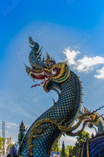 Beautiful blue naga sculpture with blue sky and white cloud on the sunny day at the public temple  Wat Rong Sua Ten  Chiang Rai  Thailand. Naga is a very great snake  found in the Buddhism temples.